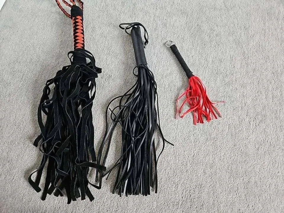 Three flogger-style tools on a carpet, matching kink and BDSM dating topics for adults in the US