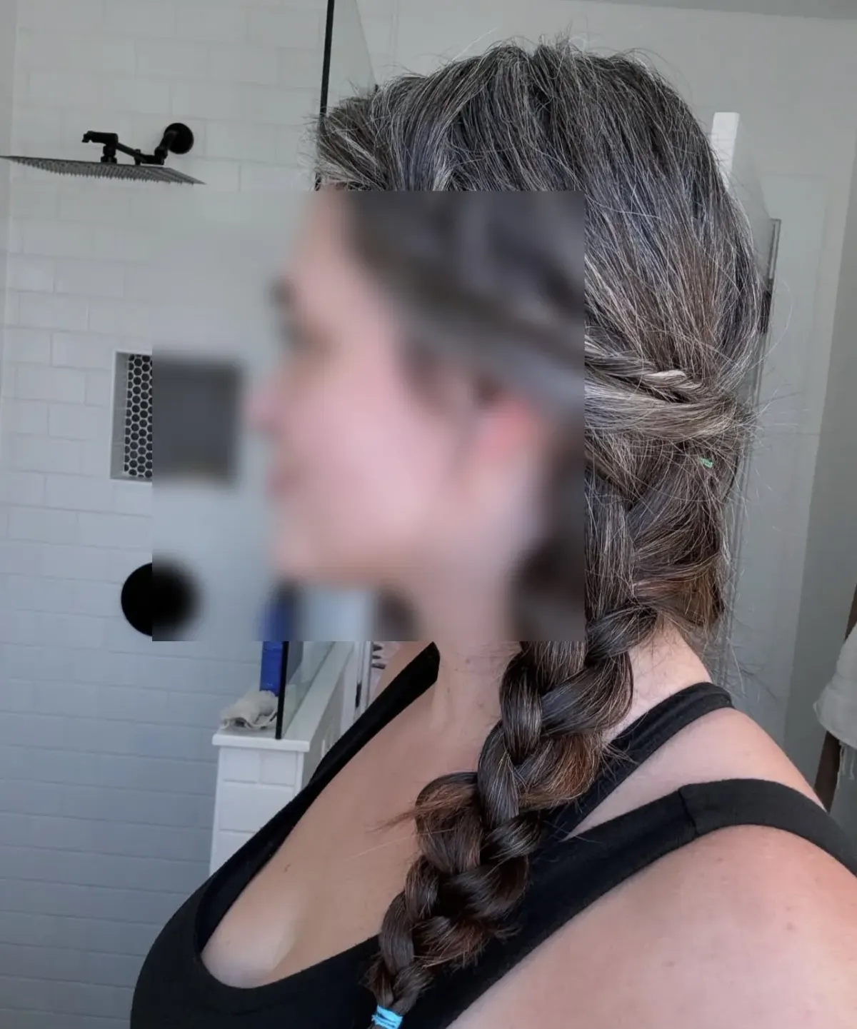 Person with braided gray and brown hair in a bathroom for a guide to comparing kink-aware dating app options